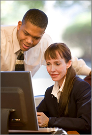 Photo of man and woman looking at computer monitor.